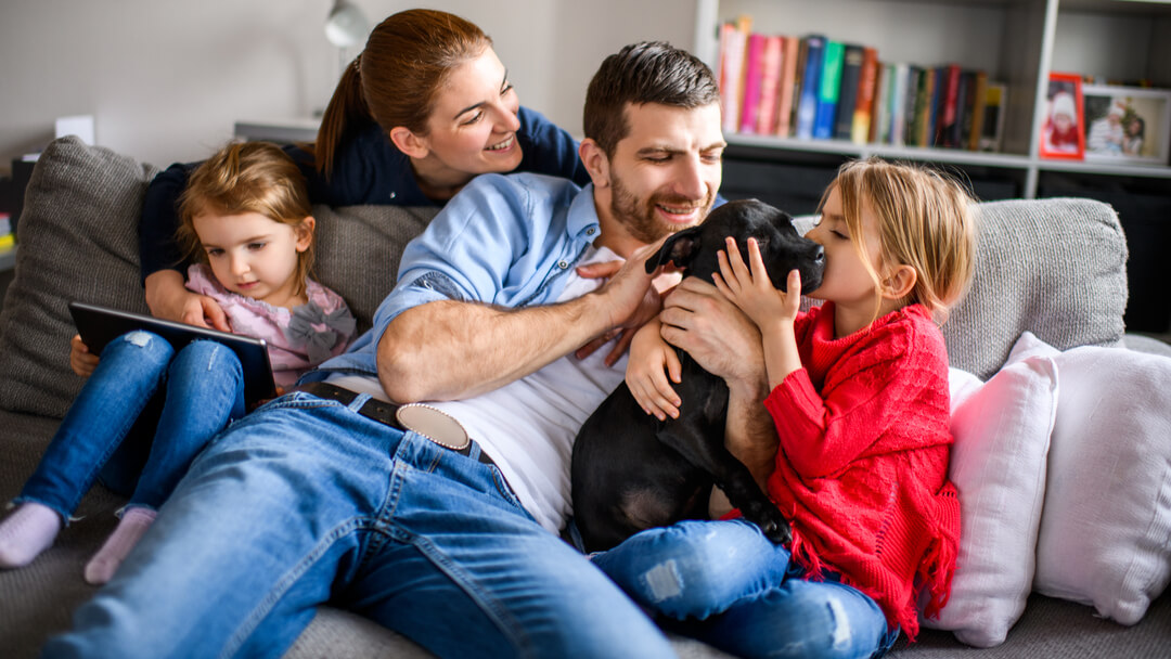 Een gezin van vier speelt met een zwarte puppy