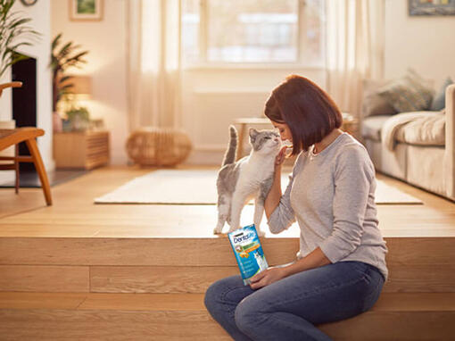 vrouw met dentalife kattensnacks naast kat